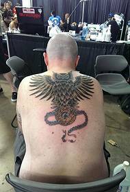 Mann mat schéine Pendant an Owl Tattoobiller op der Réck