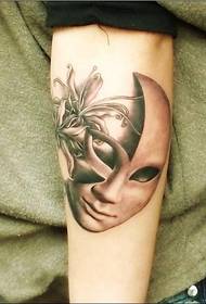 Braccia con una maschera e un tatuaggio sull'altro lato