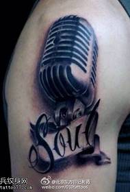 Unha tatuaxe de micrófono realista e dominante no ombreiro