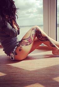 Kaunis tatuoitu kuva kauniilla naisen jaloilla