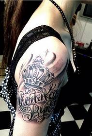Lámh láimhe faiseanta ban ag lorg pictiúr tattoo coróin litir