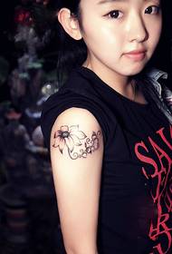 Маленька красива дівчина озброює свіжі квіти татуювання фотографії