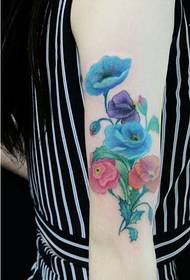 Moteriškos rankos mada, atrodanti spalvingu gėlių tatuiruotės modeliu