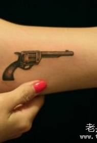 Mergaitės rankos mažas ir stilingas mažo pistoleto tatuiruotės raštas