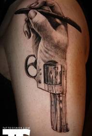 Brazo con una mano creativa y un tatuaje de pistola