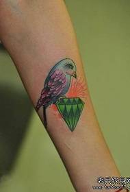 Braccio da bambina con un tatuaggio colorato di uccelli con diamante