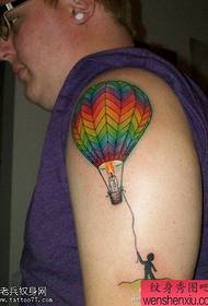 Tatoveringer med varm luftballong i storarm blir delt av tatoveringer