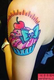 Tetovējumu šovu joslā tika ieteikts rokas karikatūras torte ķiršu tetovējums