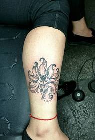 ett svartgrått lotus tatueringsmönster vid kalven