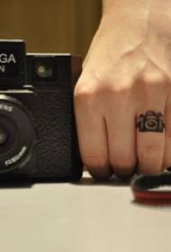 Tatuaggio con le dita sull'immagine nera e grigia del tatuaggio della macchina fotografica del braccio della ragazza del piccolo modello