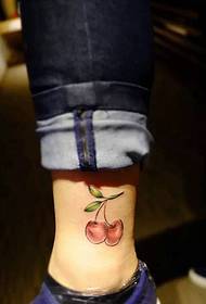 en streng tatoveringer med kirsebær som faller på leggen
