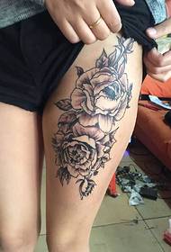 бедра девушки с двумя черно-белыми цветочными татуировками