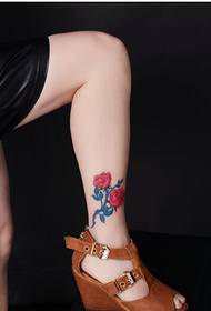 De benen van de mooie vrouw zien er alleen uit mooie foto's van het tattoo-patroon van rozen