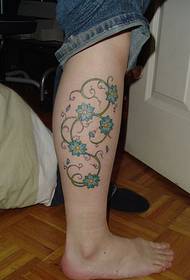 Muodikkaat jalat kauniilla näköisillä viiniköynnöksillä ja kukilla tatuointikuvilla