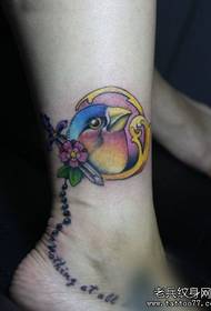 Дівочі ніжки з красивим кольоровим малюнком татуювання птахів