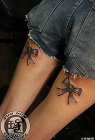 Espectáculo de tatuaxes, recomenda un traballo de tatuaje de arco nas pernas dunha muller
