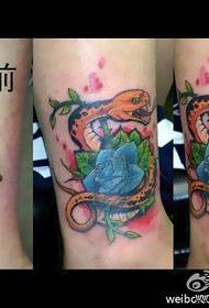 un serpente e un motivo a tatuaggio rosa sulla gamba della ragazza