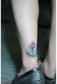 Jenteben med vakker tatoveringsmønster for bue og anker