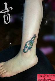 Le gambe della bella ragazza sono popolari con note musicali e tatuaggi