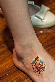 kaunis ja kaunis vaahteranlehden tatuointikuva jalan takana