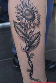 un motivo tatuaggio girasole grigio nero sulla gamba