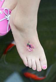 e flotte klenge Blummen Tattoo op der Instep vum Meedchen