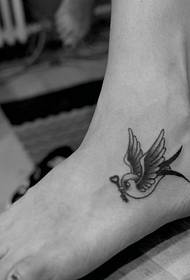 un piccolo tatuaggio rondine sul collo del piede
