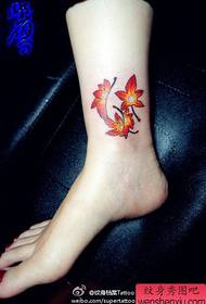 malgranda kaj bela kolora maple folia tatuaje ĉe la maleolo de la knabino