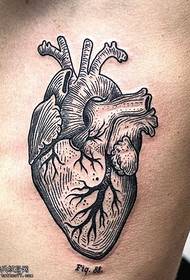 Petto con un disegno del tatuaggio a cuore pulsante