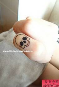 Moters pirštų kūrybinis kaukolės tatuiruotės darbas
