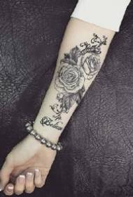 Aprecie o padrão de tatuagem preto-cinza no braço pequeno