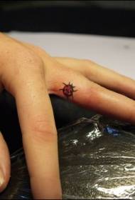 Painted little ladybug tattoo pattern on the inside of the finger
