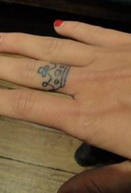 Motivo a tatuaggio con piccola corona sul dito