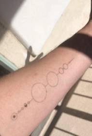 Tatuatge minimalista al braç masculí sobre tatuatge negre i rodó