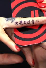 Lytse Sanskrit-tatoet op 'e finger