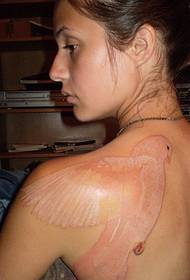 Onzichtbare tattoo-foto van een knappe grote duif op de linkerrug van de vrouw