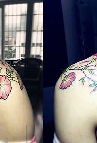 Modeli i bukur i tatuazheve me lule në shpatullat e një djali personalitet