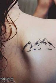 uma pequena tatuagem de montanha no ombro