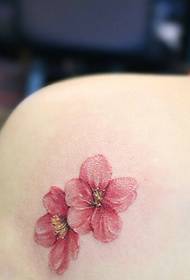 एका मुलीच्या खांद्याखाली पडणारा पाकळ्याचा टॅटू टॅटू