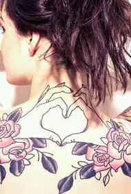 Prekrasna djevojka s cvjetnim i srčanim tetovažom na ramenu