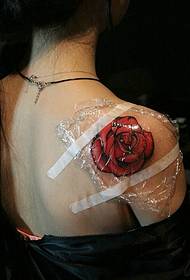 El patró de tatuatge de rosa vermella sota la fragant espatlla és molt femení