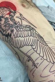 Padrão de tatuagem de guindaste sob o sol vermelho da barriga