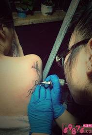 Изображение сцены производства татуировки бабочка на плече девушки