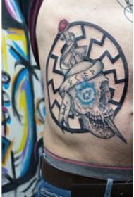 Tetovējuma sānu jostasvietas vīrieša zēna sānu vidukļa duncis un galvaskausa tetovējuma attēls