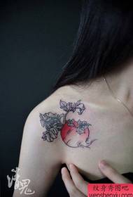 Bello modello femminile del tatuaggio del ravanello sulla spalla di una ragazza