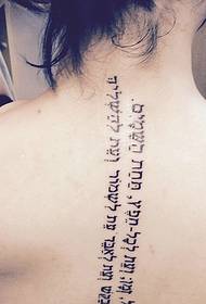 punggung seksi duwe tato Sanskrit sing sederhana