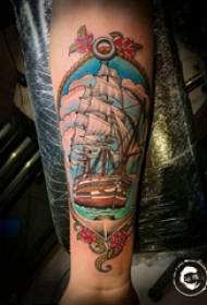 Arm tattookuva pojan käsivarsi värillisellä purjeveneen tatuoinnilla