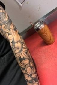 Braccio della ragazza del tatuaggio del fiore sopra l'immagine del tatuaggio del fiore di arte