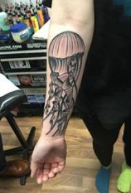 Bracciu di una ragazza di mudellu di tatuaggi di medusa nantu à una foto di tatuaggi di medusa grisa negra