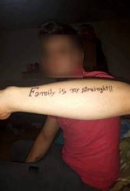 Håndtatoveret engelsk alfabetets drengearm på sort engelsk tatoveringsbillede